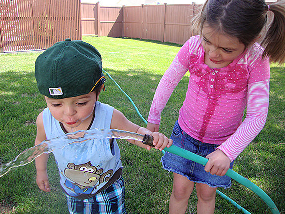 Kids drinking clean, safe water from a backyard hose