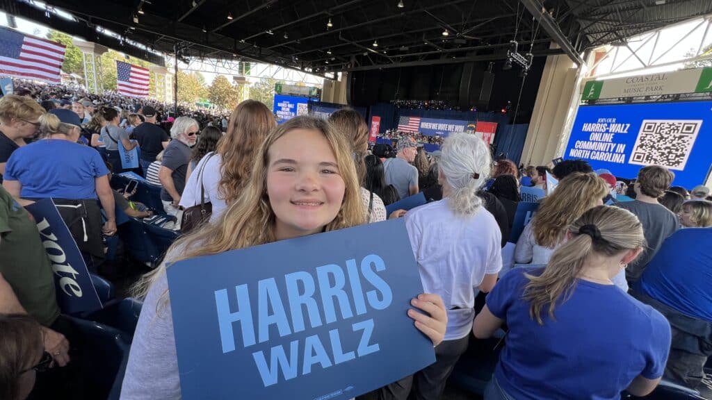 Hallsey (12 years old), holds a Harris-Walz sign at a rally